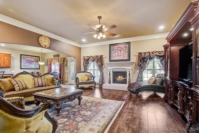 living room with dark wood-type flooring, crown molding, and ceiling fan