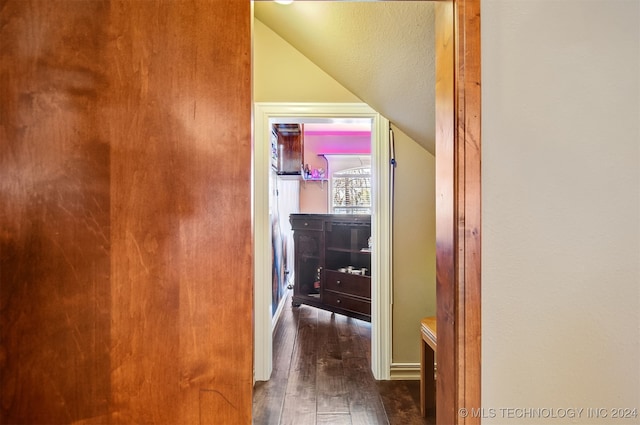 hallway featuring lofted ceiling, dark hardwood / wood-style floors, and a textured ceiling