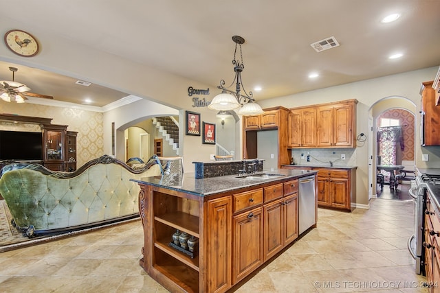 kitchen with an island with sink, hanging light fixtures, stainless steel appliances, dark stone counters, and crown molding