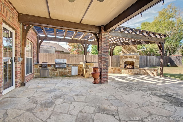 view of patio / terrace with exterior kitchen, an outdoor stone fireplace, a grill, and a pergola