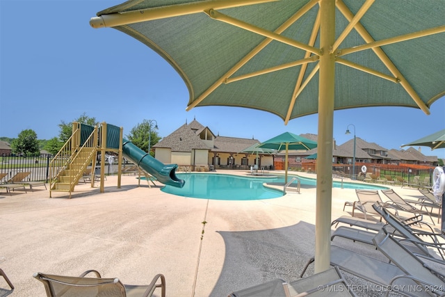 view of pool with a patio, a water slide, and a playground