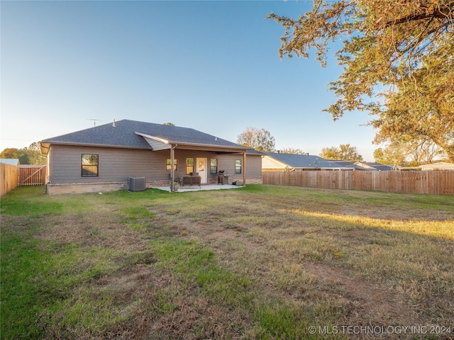 rear view of house with central AC, a patio, and a lawn