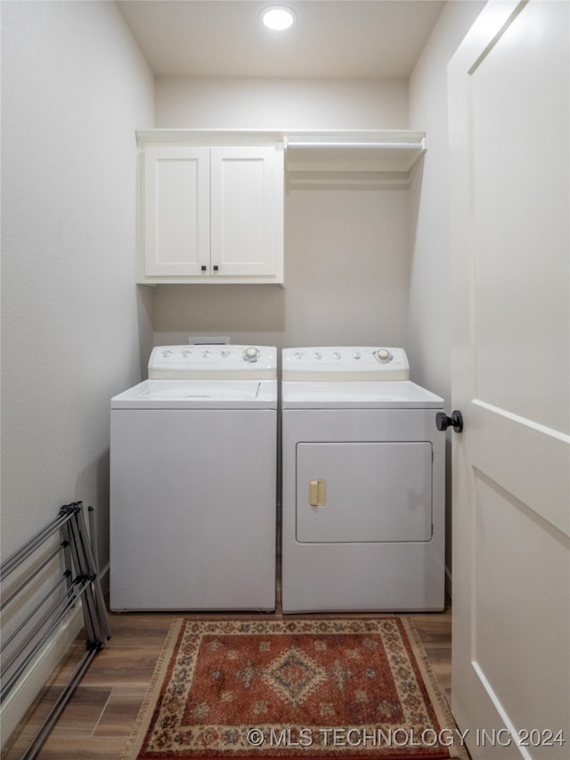 laundry room featuring cabinets, independent washer and dryer, and dark hardwood / wood-style floors