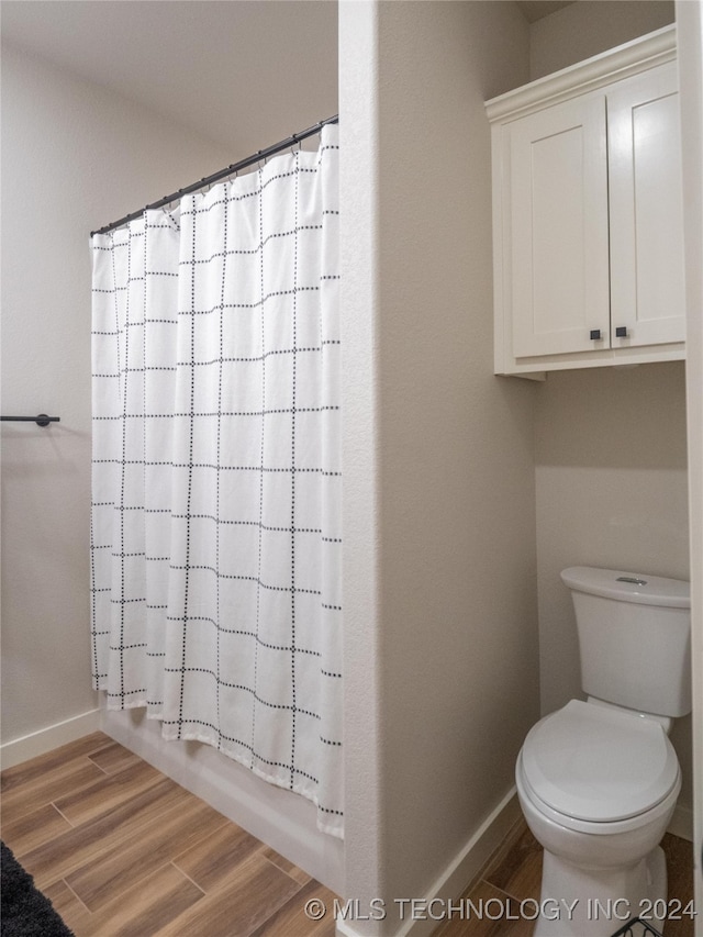 bathroom featuring toilet, hardwood / wood-style flooring, and shower / bath combo