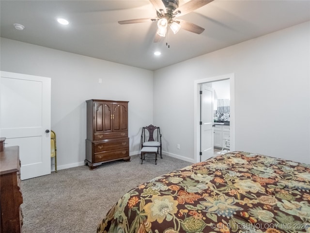 bedroom with ensuite bathroom, light colored carpet, and ceiling fan