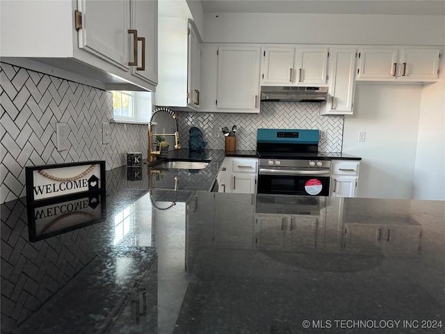 kitchen with tasteful backsplash, sink, stainless steel range oven, white cabinetry, and dark stone countertops