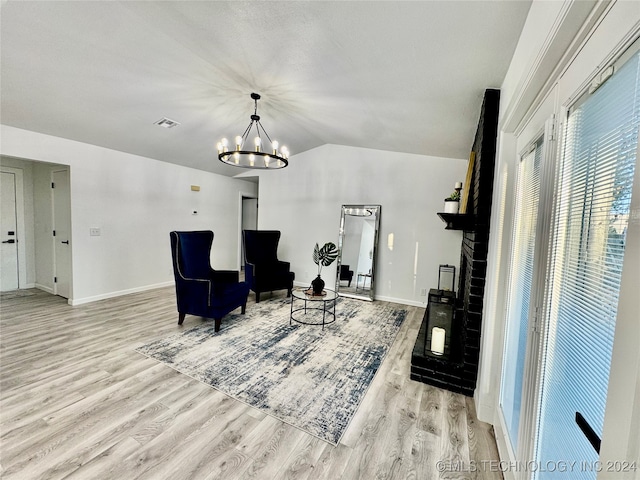 living area with an inviting chandelier, light hardwood / wood-style flooring, and vaulted ceiling