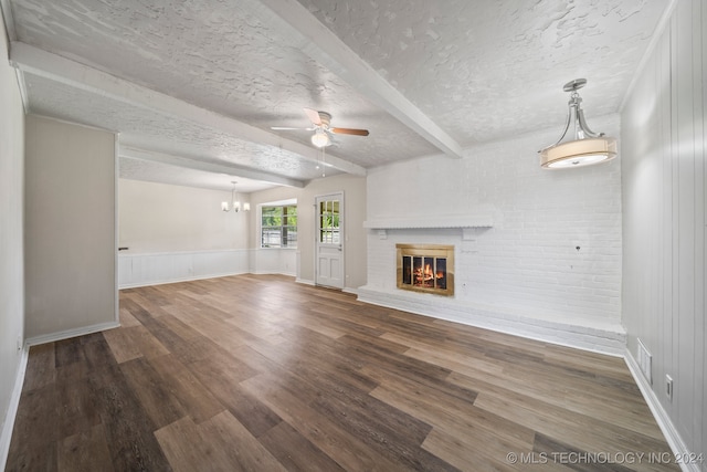 unfurnished living room with hardwood / wood-style flooring, beamed ceiling, a brick fireplace, a textured ceiling, and ceiling fan with notable chandelier