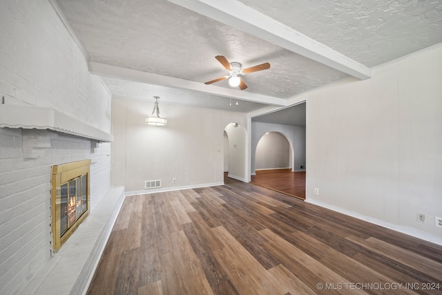 unfurnished living room featuring beamed ceiling, a textured ceiling, a fireplace, and wood-type flooring