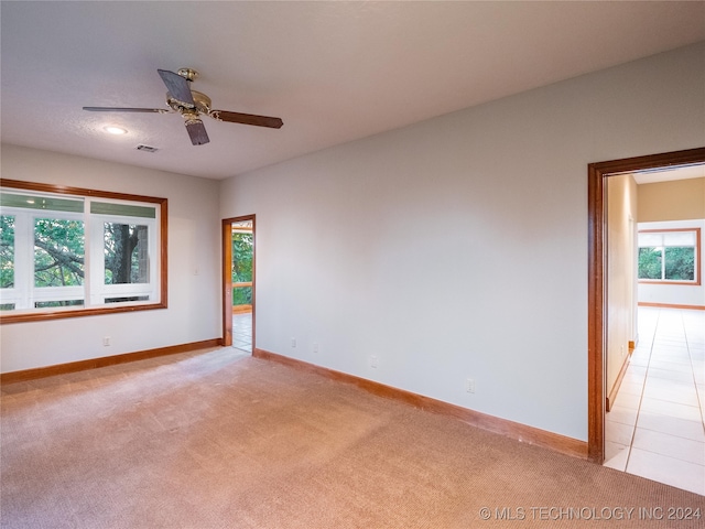 empty room with light carpet, a wealth of natural light, and ceiling fan