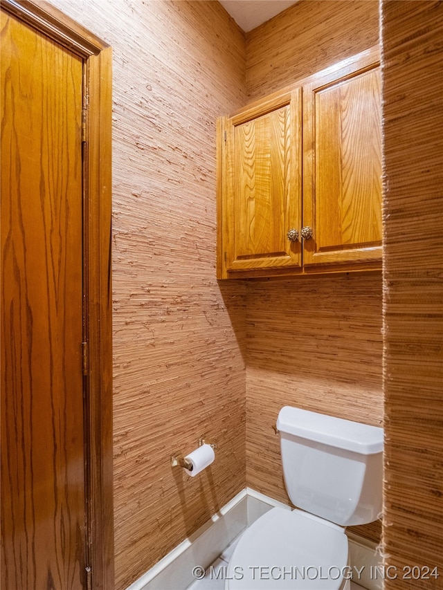 bathroom featuring toilet and wood walls