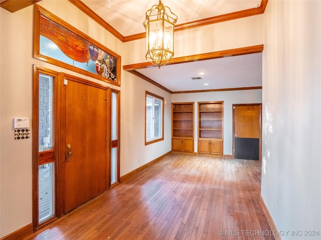 foyer with crown molding, a notable chandelier, and hardwood / wood-style flooring