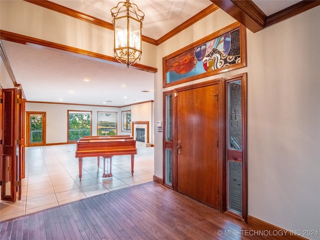 foyer featuring crown molding, light hardwood / wood-style flooring, and an inviting chandelier