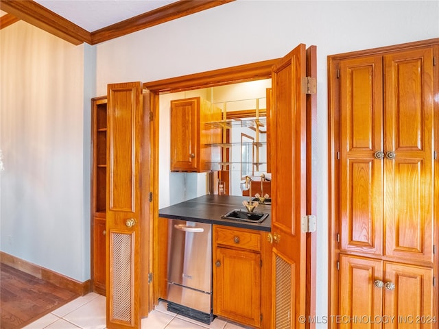 kitchen featuring crown molding, dishwasher, sink, and light tile patterned floors