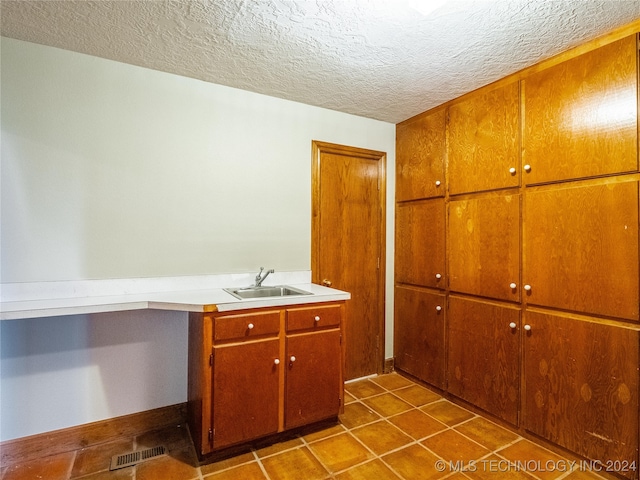 interior space featuring a textured ceiling, sink, and dark tile patterned floors