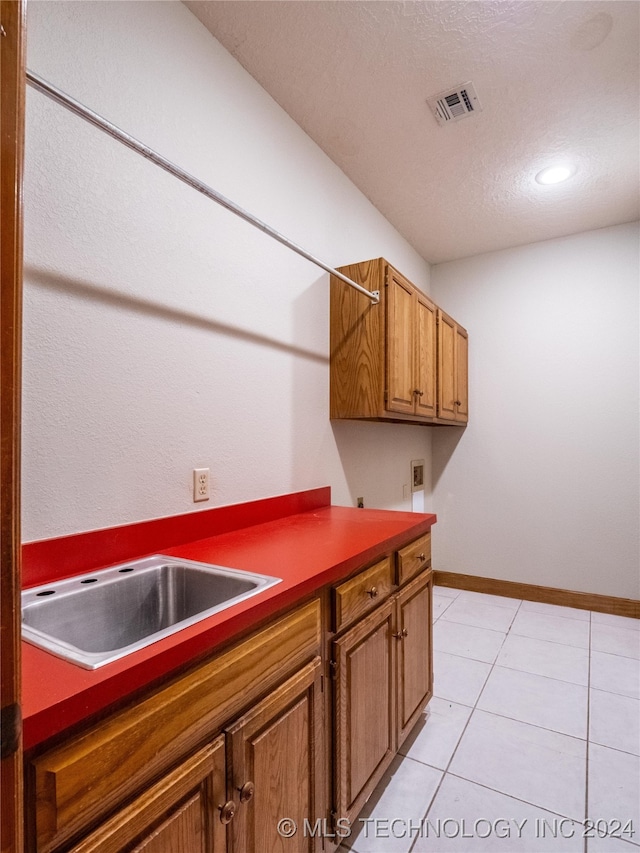 kitchen with light tile patterned floors, a textured ceiling, and sink