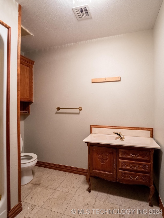 bathroom featuring vanity, a textured ceiling, and toilet