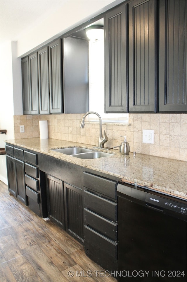 kitchen featuring black dishwasher, sink, backsplash, dark wood-type flooring, and light stone counters