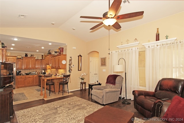 living room with dark hardwood / wood-style flooring, ceiling fan, and vaulted ceiling