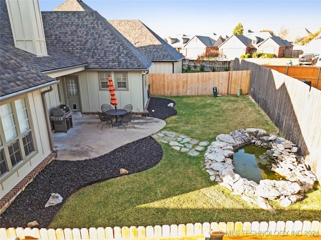 view of yard featuring a small pond and a patio area