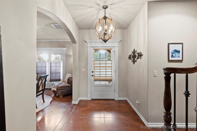 entryway with a chandelier and crown molding