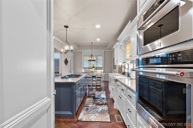 kitchen featuring blue cabinets, sink, white cabinetry, decorative light fixtures, and stainless steel appliances