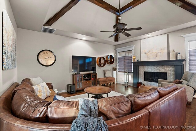 living room with vaulted ceiling with beams, dark wood-type flooring, a tile fireplace, and ceiling fan