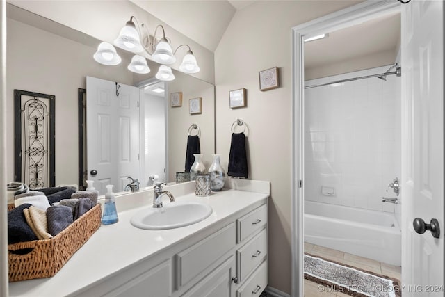 bathroom with vanity, tiled shower / bath combo, lofted ceiling, and tile patterned floors