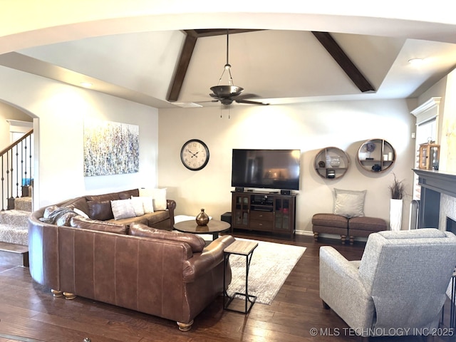 living room with dark wood-type flooring, ceiling fan, and vaulted ceiling with beams