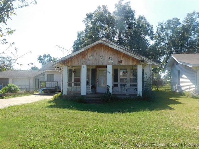 bungalow featuring covered porch and a front yard