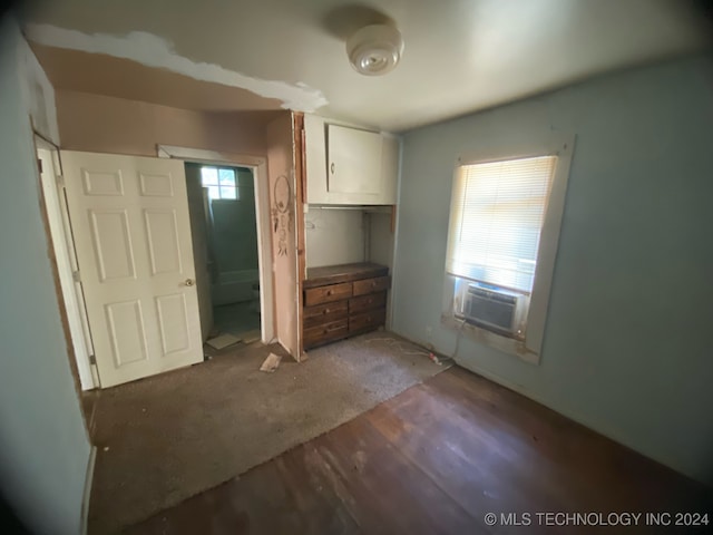 unfurnished bedroom with cooling unit, multiple windows, a closet, and dark hardwood / wood-style flooring