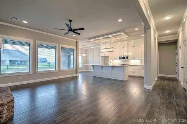 kitchen featuring white cabinetry, dark hardwood / wood-style flooring, pendant lighting, and a center island with sink