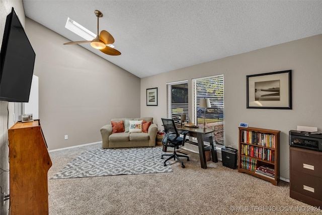 carpeted office with ceiling fan, vaulted ceiling with skylight, and a textured ceiling