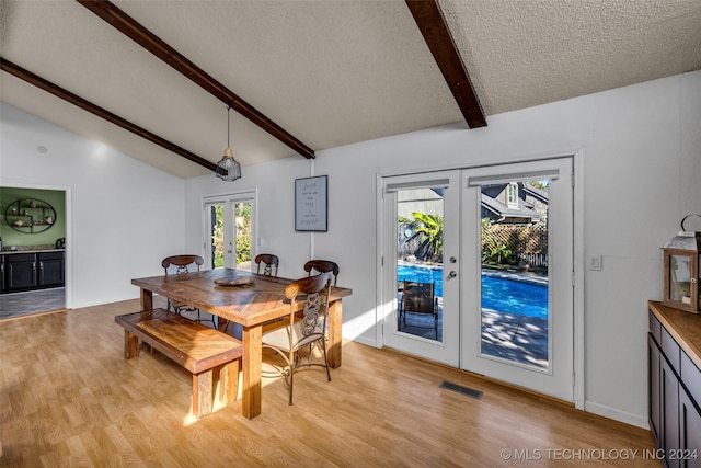 dining space featuring light hardwood / wood-style flooring, lofted ceiling with beams, french doors, and a textured ceiling