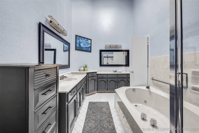 bathroom with tile patterned floors, vanity, and tiled bath