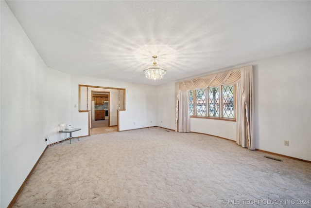 empty room featuring carpet floors and an inviting chandelier