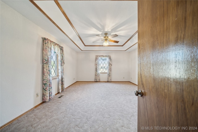 carpeted empty room with a tray ceiling and ceiling fan