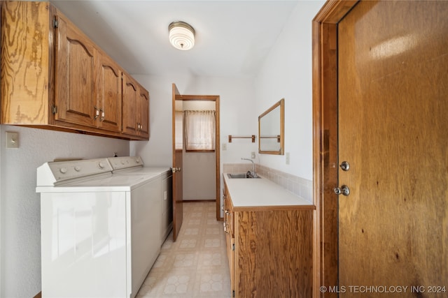 clothes washing area with cabinets, sink, and washing machine and dryer