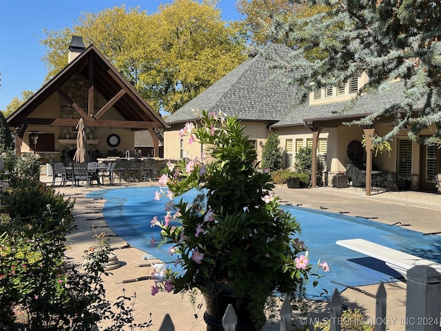 view of pool with a diving board and a patio area