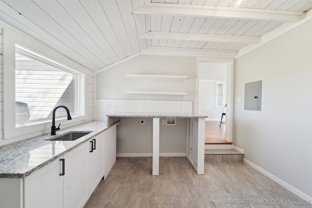 kitchen with sink, lofted ceiling with beams, electric panel, white cabinetry, and light stone counters