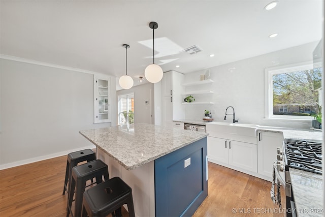 kitchen with white cabinets, light hardwood / wood-style flooring, stainless steel appliances, sink, and a center island