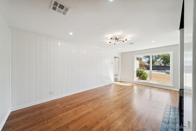 unfurnished room featuring a notable chandelier and hardwood / wood-style floors