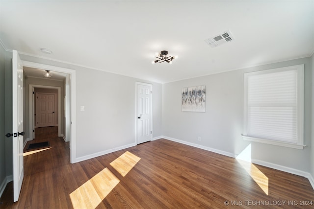 empty room featuring ornamental molding and dark hardwood / wood-style flooring