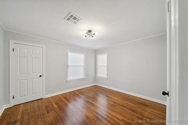 empty room featuring crown molding and wood-type flooring