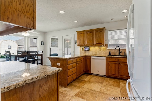 kitchen featuring white appliances, kitchen peninsula, sink, a textured ceiling, and tasteful backsplash