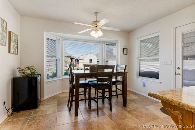 dining area featuring ceiling fan and a textured ceiling