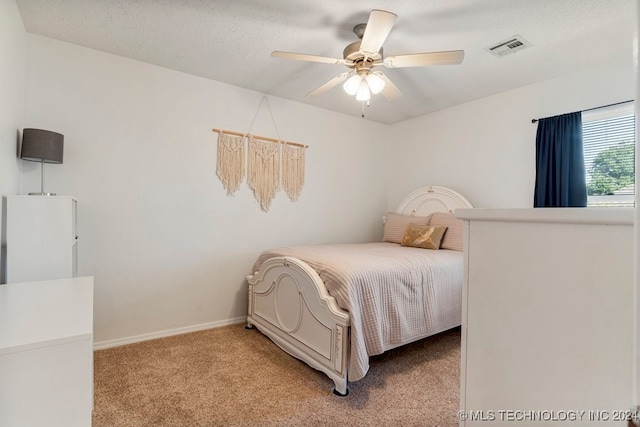 bedroom with ceiling fan, light colored carpet, and a textured ceiling