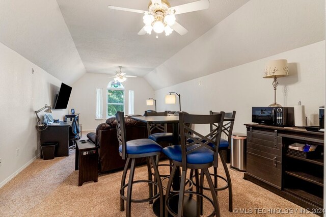 dining area with ceiling fan, light colored carpet, and vaulted ceiling