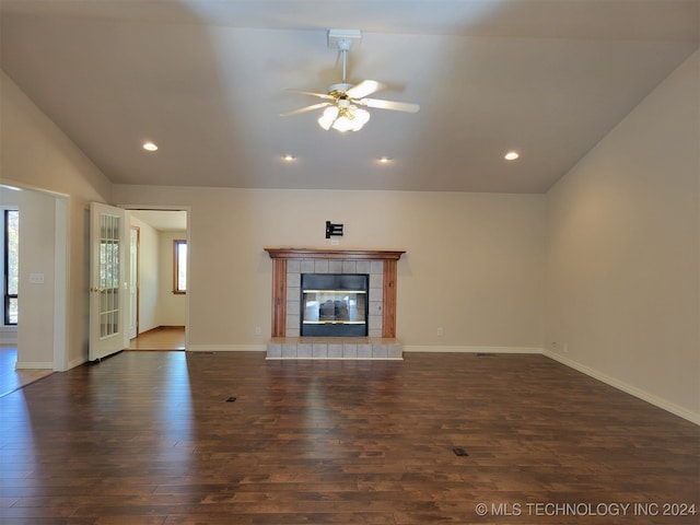 unfurnished living room featuring dark wood-type flooring, a tiled fireplace, vaulted ceiling, and ceiling fan