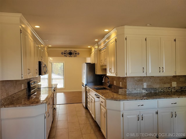 kitchen with appliances with stainless steel finishes, sink, backsplash, white cabinets, and light tile patterned floors